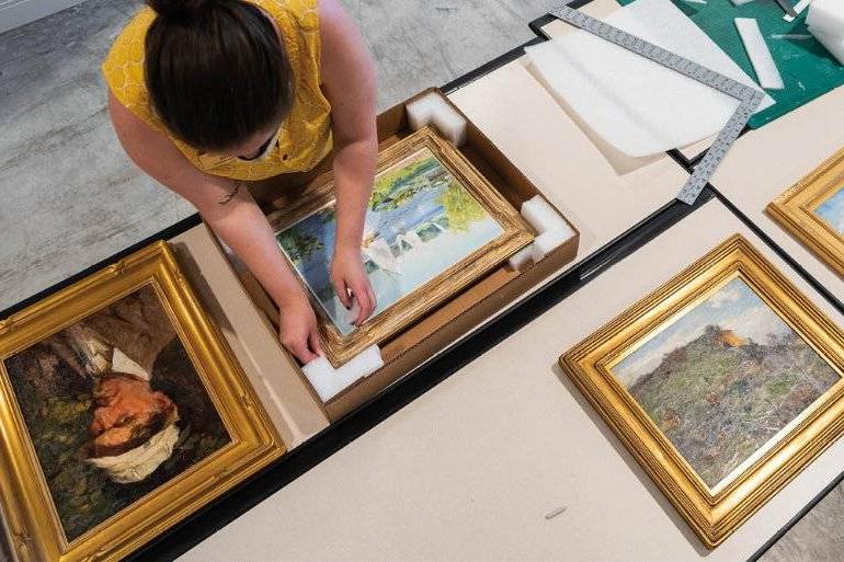 woman packing framed artwork into boxes